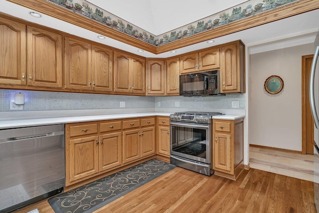 kitchen featuring stainless steel appliances, light countertops, tasteful backsplash, and light wood finished floors