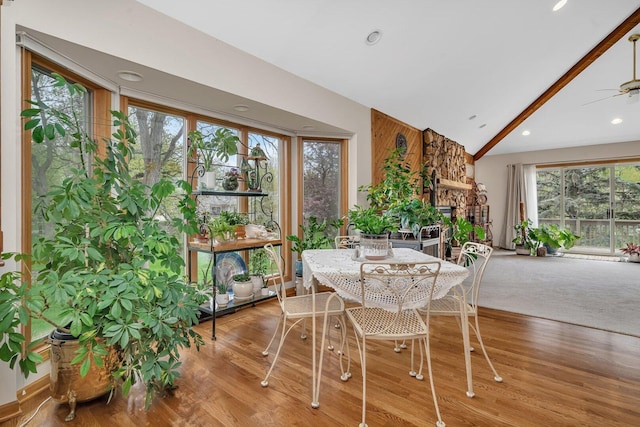 dining space with vaulted ceiling, ceiling fan, a fireplace, wood finished floors, and recessed lighting