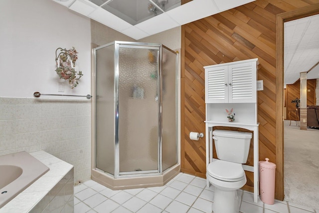 bathroom featuring toilet, a stall shower, wood walls, tile patterned flooring, and a bath