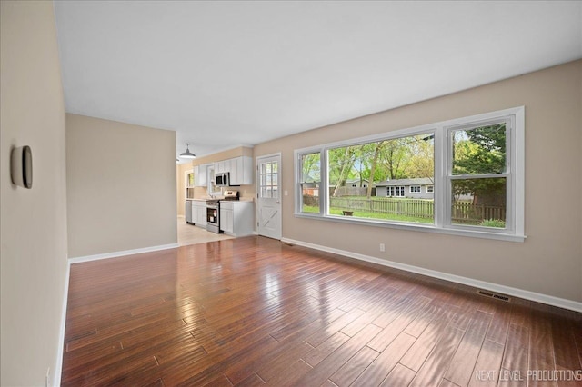16 Circle Dr E, Montgomery, IL 60538 - unfurnished living room featuring baseboards, visible vents, and wood finished floors