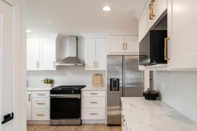 kitchen featuring light wood-style flooring, wall chimney exhaust hood, white cabinets, black appliances, and backsplash