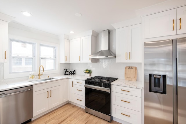 kitchen featuring a sink, white cabinetry, wall chimney exhaust hood, stainless steel appliances, and tasteful backsplash