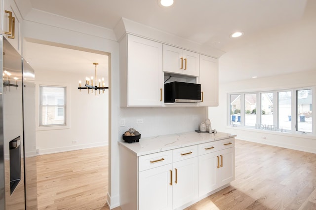 kitchen featuring white cabinetry, light wood finished floors, stainless steel fridge, and an inviting chandelier