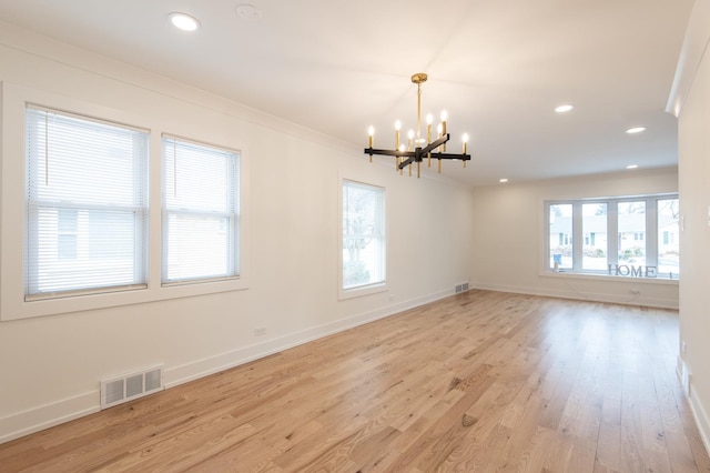 spare room with a chandelier, ornamental molding, a wealth of natural light, and visible vents