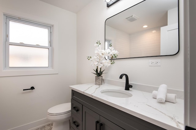 bathroom with baseboards, toilet, vanity, and visible vents