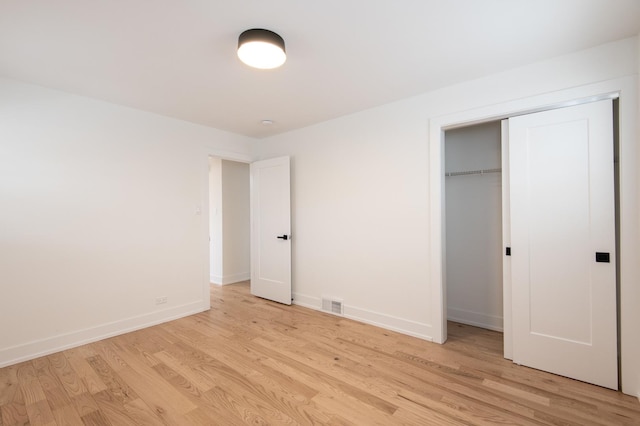unfurnished bedroom with a closet, light wood-style floors, visible vents, and baseboards
