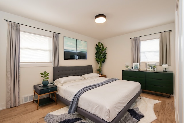 bedroom featuring light wood finished floors and visible vents