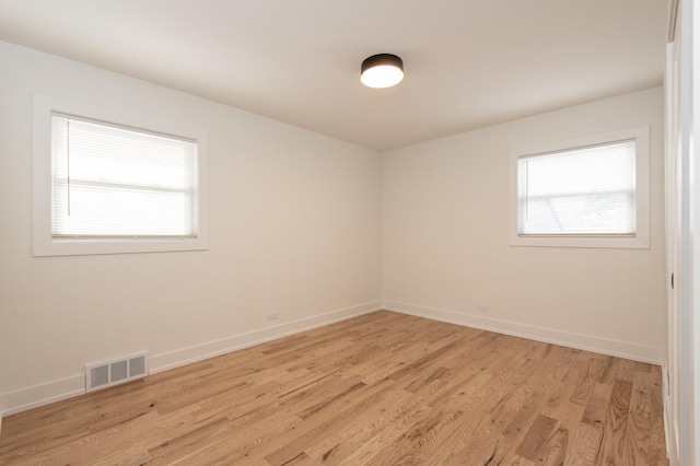 spare room featuring baseboards, visible vents, and light wood-style floors
