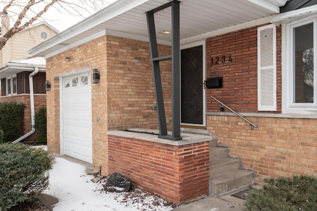 view of exterior entry with brick siding and an attached garage