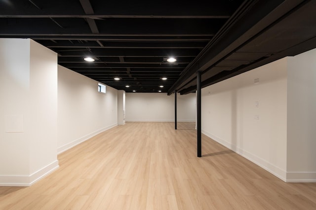 finished below grade area with baseboards and wood finished floors