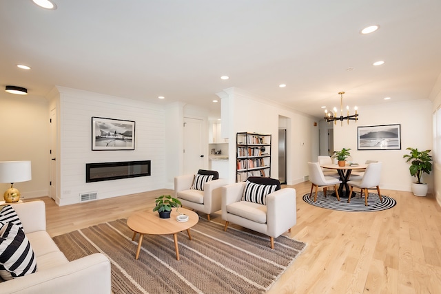 living area with an inviting chandelier, light wood-style flooring, crown molding, visible vents, and recessed lighting