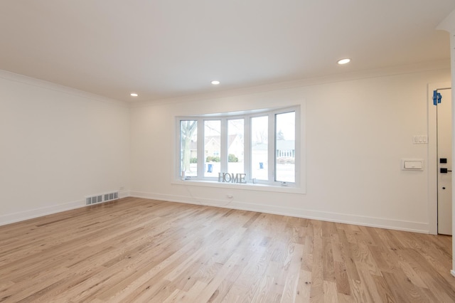 spare room with light wood-type flooring, crown molding, visible vents, and baseboards