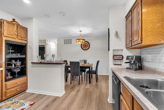 kitchen featuring brown cabinets, light wood-style floors, visible vents, and dishwasher