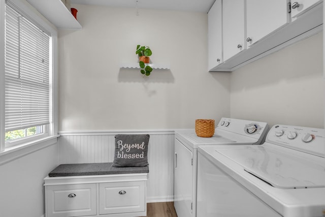 laundry area with washing machine and clothes dryer, cabinet space, and a wainscoted wall