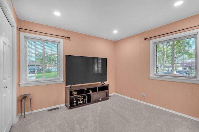 unfurnished living room with a wealth of natural light, carpet floors, baseboards, and visible vents
