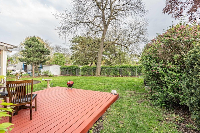 wooden deck with a yard, an outbuilding, a fenced backyard, and a storage unit