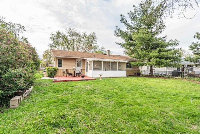 rear view of house with a sunroom, fence, a deck, and a yard