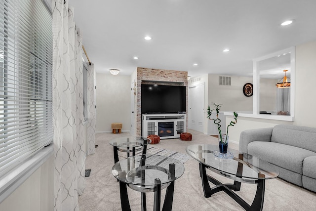 carpeted living area featuring visible vents, baseboards, a glass covered fireplace, and recessed lighting