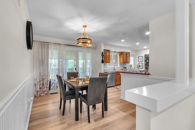 dining room featuring a healthy amount of sunlight, wainscoting, and light wood-type flooring