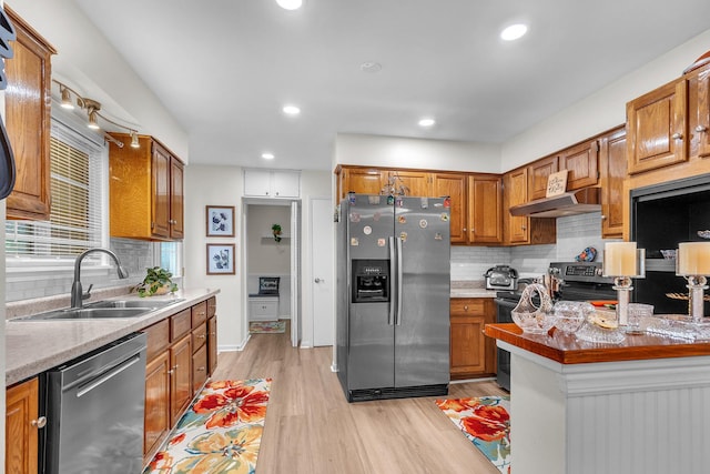 kitchen featuring backsplash, light wood finished floors, appliances with stainless steel finishes, and a sink