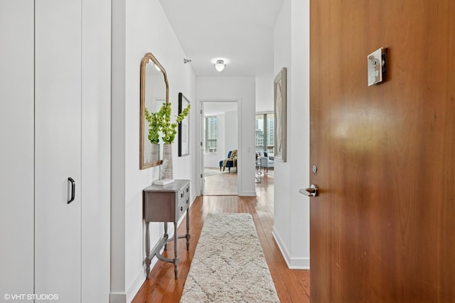 corridor with light wood-type flooring and baseboards