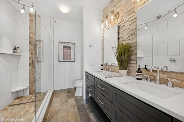 full bath with toilet, backsplash, a tile shower, double vanity, and stone finish floors