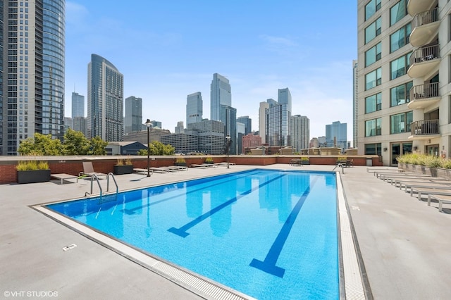 community pool with a skyline view and a patio area
