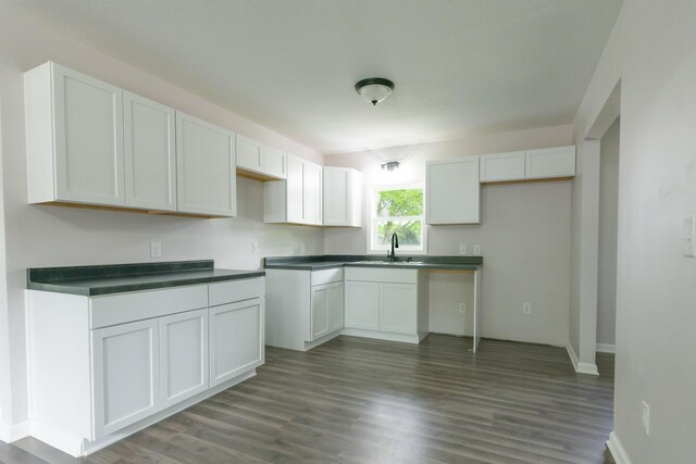 211 N Center St, Buda, IL 61314 - kitchen with a sink, dark wood-type flooring, dark countertops, white cabinetry, and baseboards