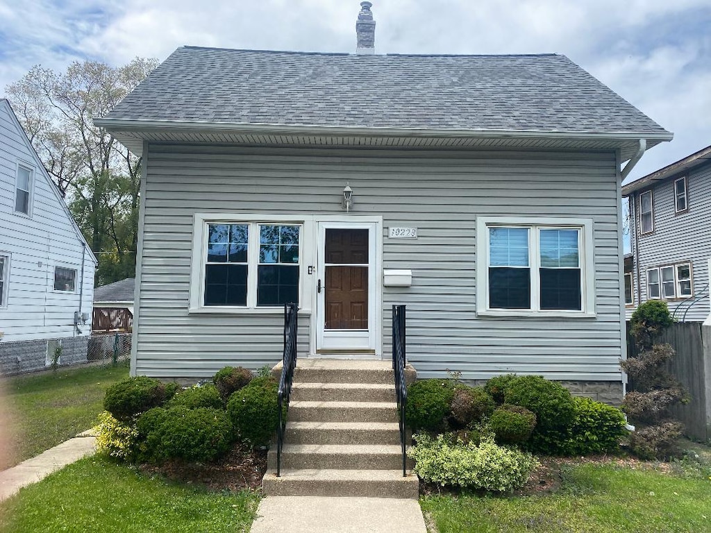 10228 S Sawyer Ave, Evergreen Park, IL 60805 - view of front of home featuring a shingled roof, fence, and a chimney