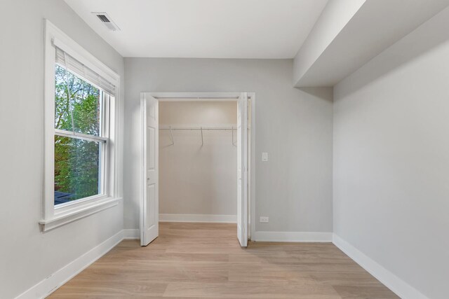 unfurnished bedroom featuring light wood-style floors, baseboards, and a closet