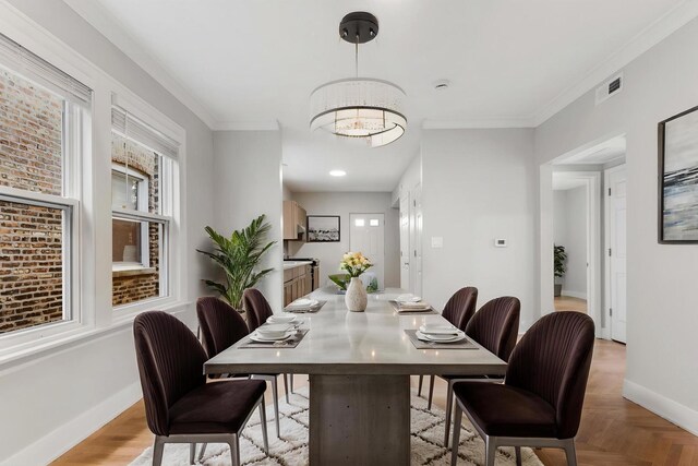 dining space with baseboards, a chandelier, and crown molding