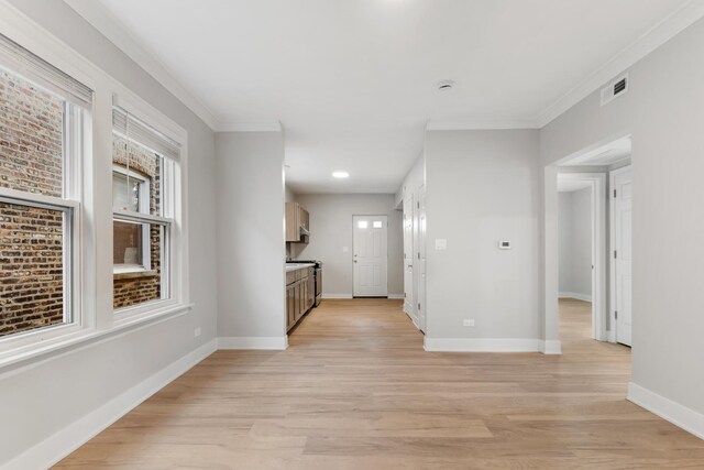 hallway with light wood-type flooring, baseboards, and crown molding