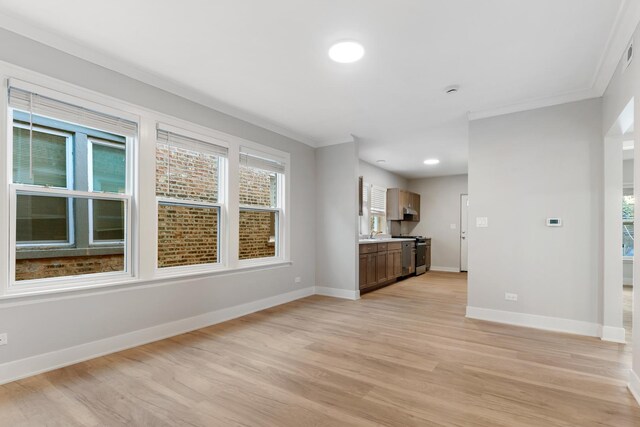 unfurnished living room featuring light wood-style flooring, baseboards, and crown molding