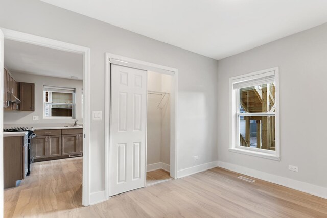 unfurnished bedroom with light wood-style floors, a sink, and baseboards