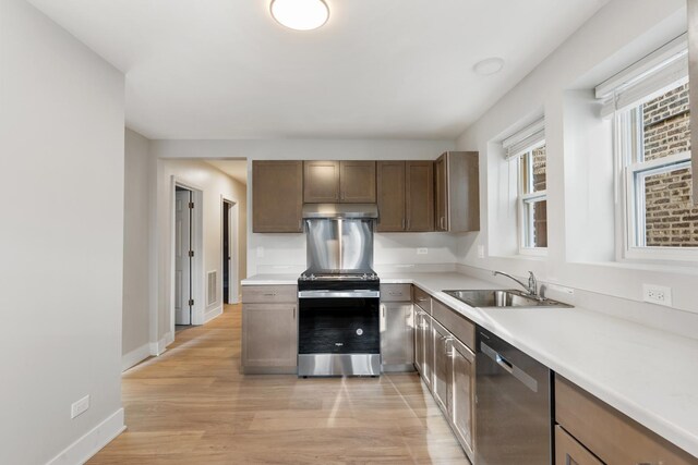 kitchen featuring a sink, appliances with stainless steel finishes, light wood-style floors, and light countertops