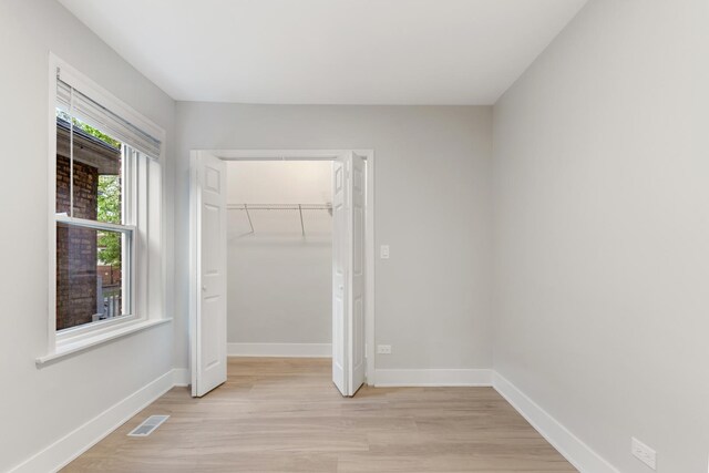 unfurnished bedroom featuring light wood-style flooring, baseboards, and a closet
