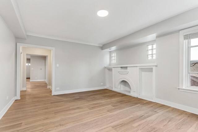 unfurnished living room featuring light wood-type flooring, baseboards, a brick fireplace, and crown molding