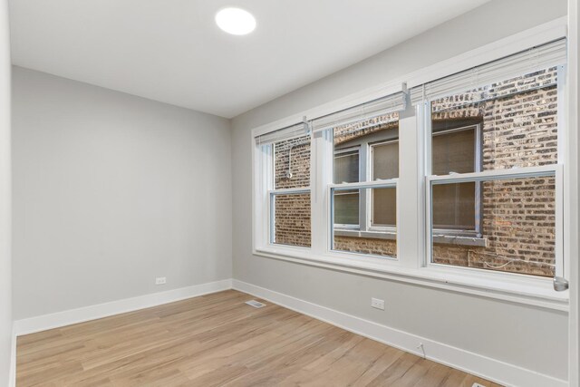 spare room featuring baseboards and light wood finished floors