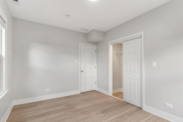 unfurnished bedroom featuring light wood-style flooring, baseboards, and a closet