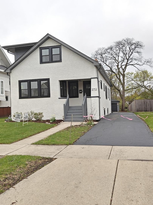 bungalow with stucco siding, fence, a front yard, and a porch