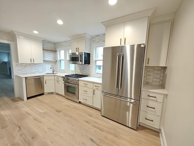 kitchen featuring light countertops, decorative backsplash, light wood-style flooring, and high quality appliances