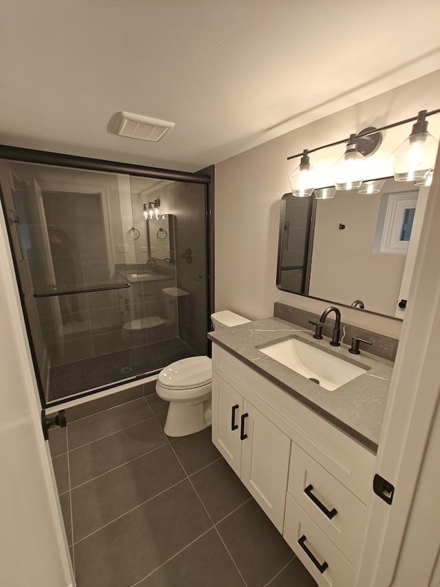 bathroom with toilet, visible vents, a shower stall, tile patterned floors, and vanity