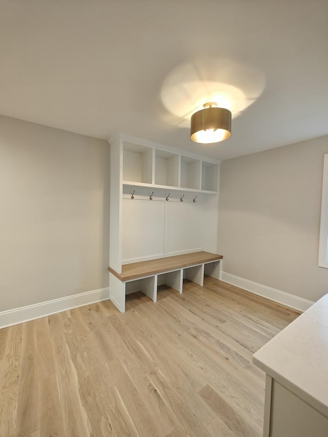 mudroom featuring light wood finished floors and baseboards