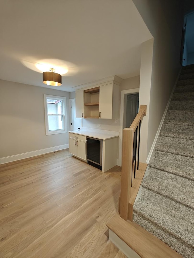 kitchen featuring light wood finished floors, open shelves, white cabinets, baseboards, and light countertops