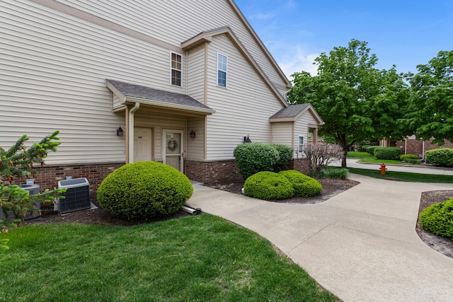 view of side of property with central AC unit and a lawn