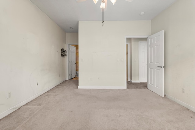 carpeted empty room featuring a ceiling fan and baseboards