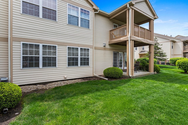 back of house with a balcony, a patio area, and a lawn
