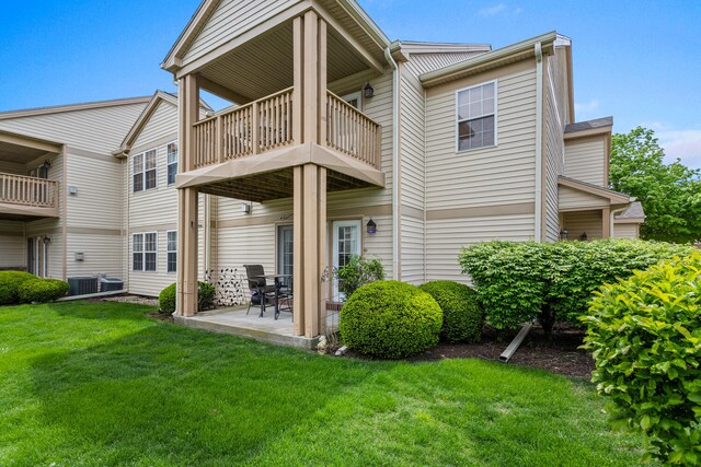 back of property with a balcony, a yard, a patio area, and central AC unit