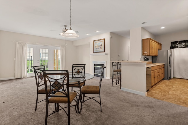 dining room with a ceiling fan, light colored carpet, baseboards, recessed lighting, and a glass covered fireplace