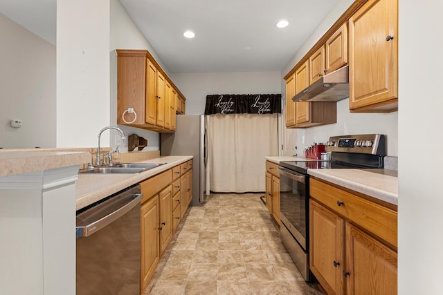 kitchen featuring under cabinet range hood, stainless steel appliances, a sink, light countertops, and stone finish floors